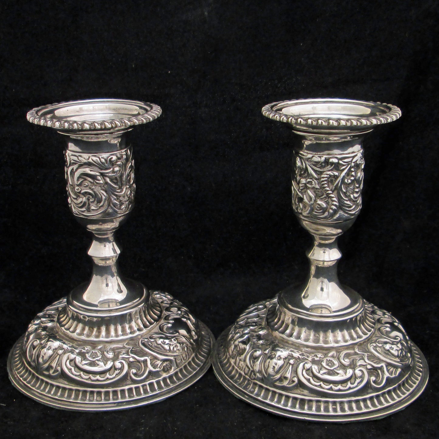 A pair of sterling silver embossed candlesticks.