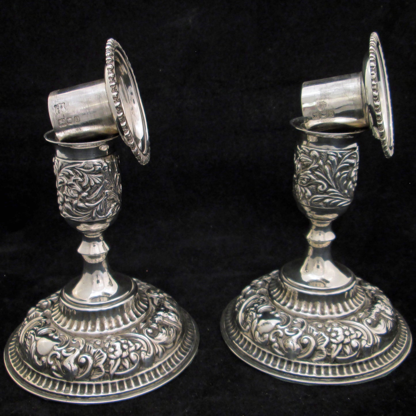 A pair of sterling silver embossed candlesticks.