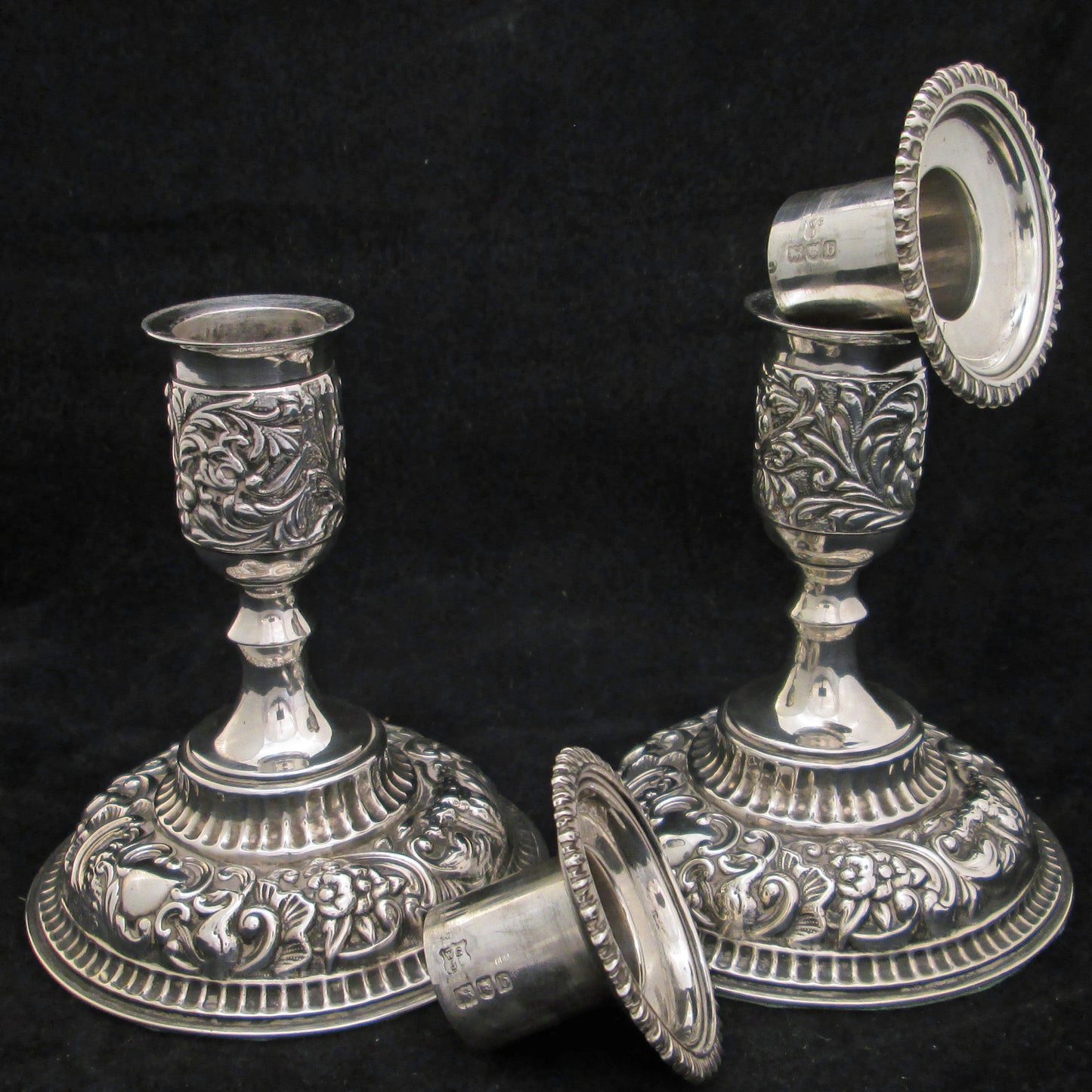 A pair of sterling silver embossed candlesticks.