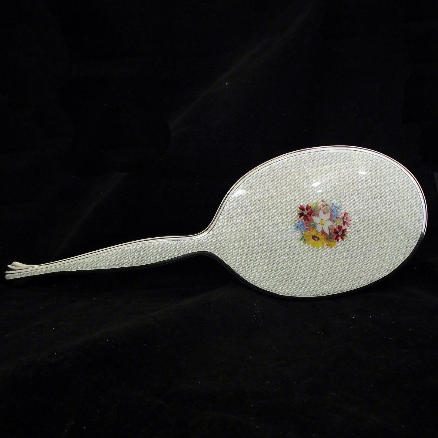 A sterling silver and enamel hand mirror.