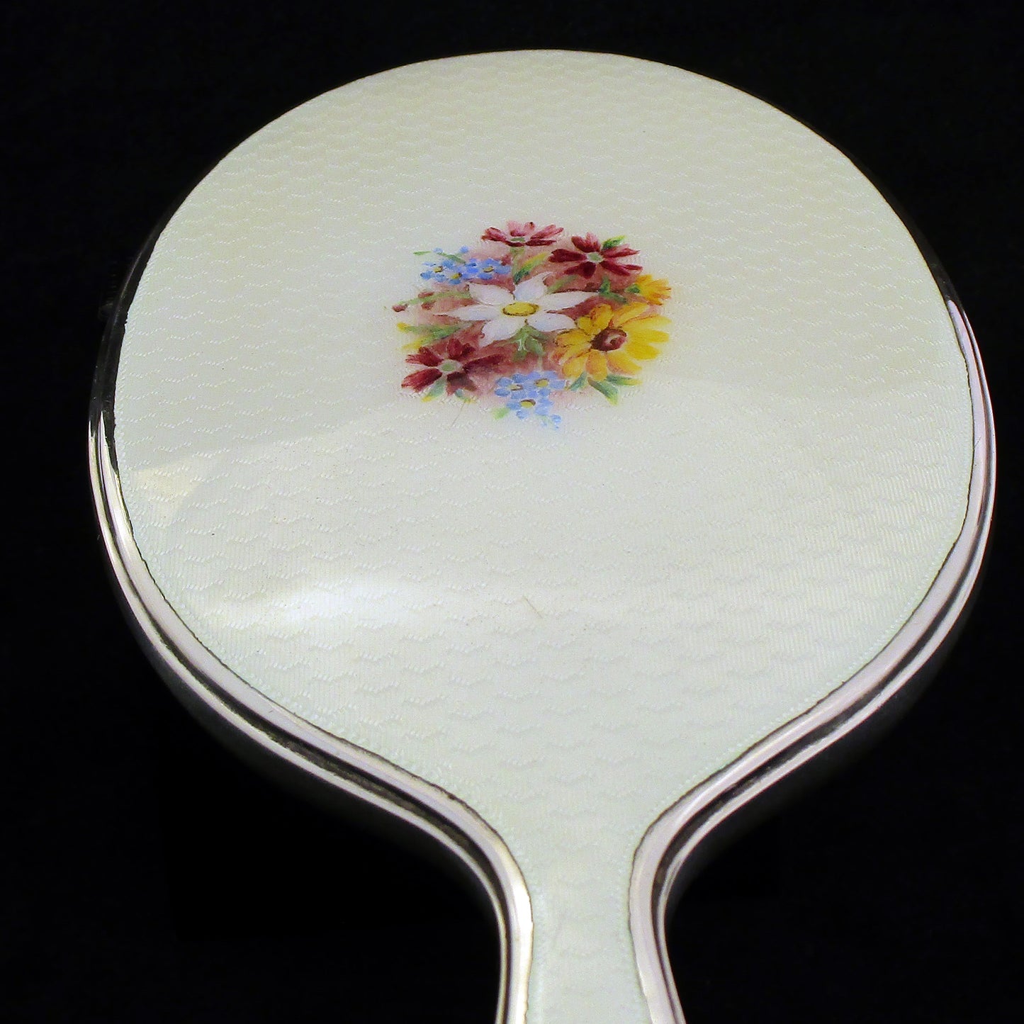 A sterling silver and enamel hand mirror.