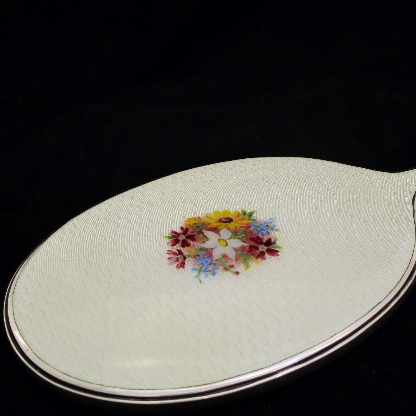 A sterling silver and enamel hand mirror.