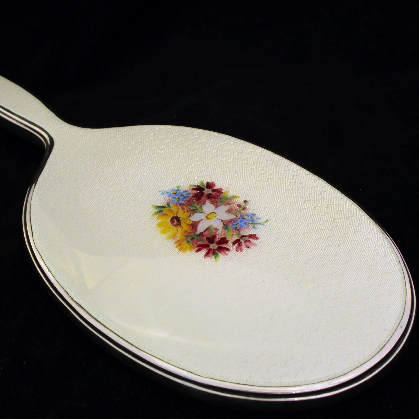 A sterling silver and enamel hand mirror.