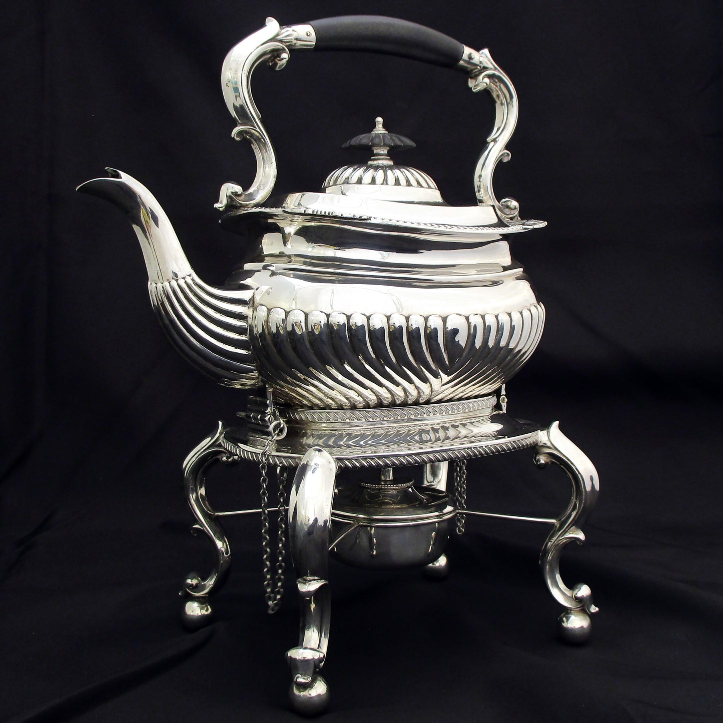 A quality sterling silver kettle on a stand.