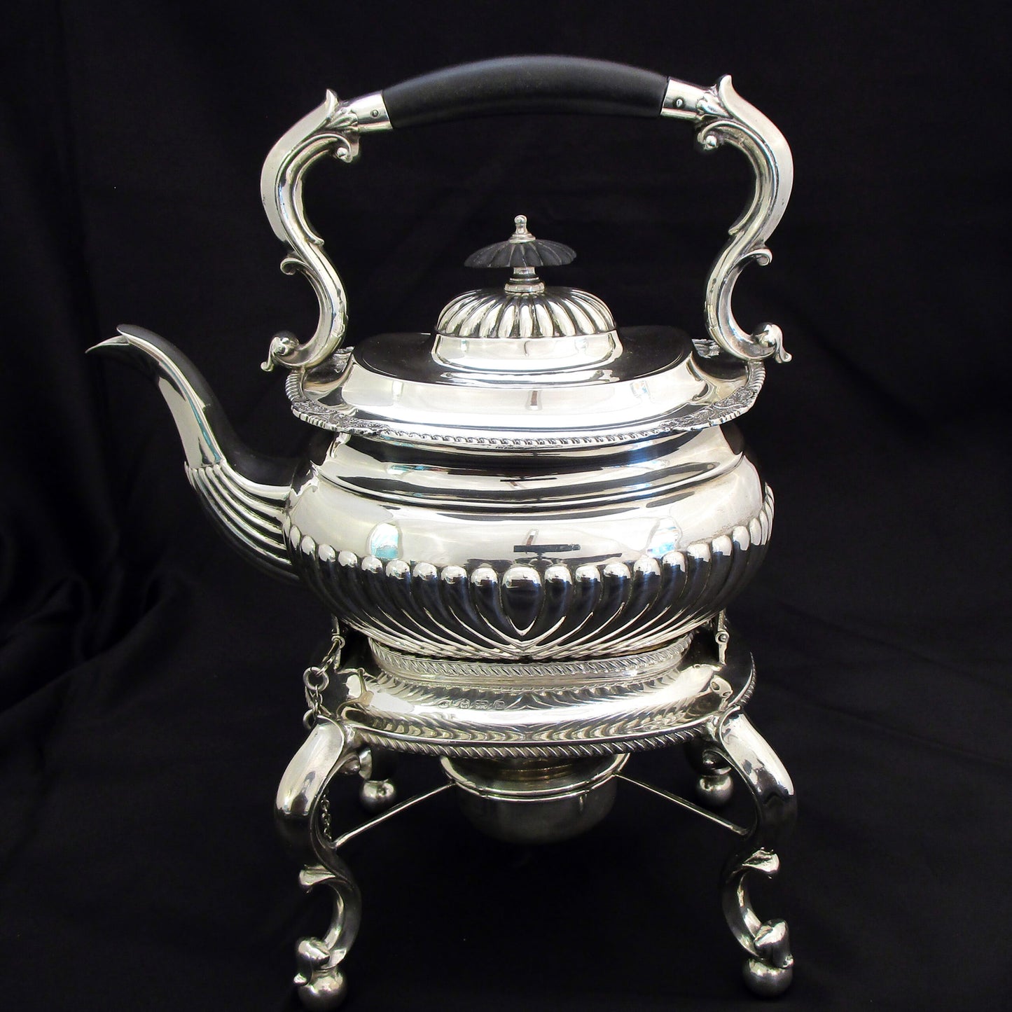 A quality sterling silver kettle on a stand.