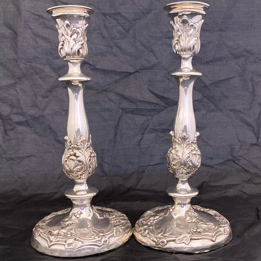 Two ornate silver candlesticks on a black background