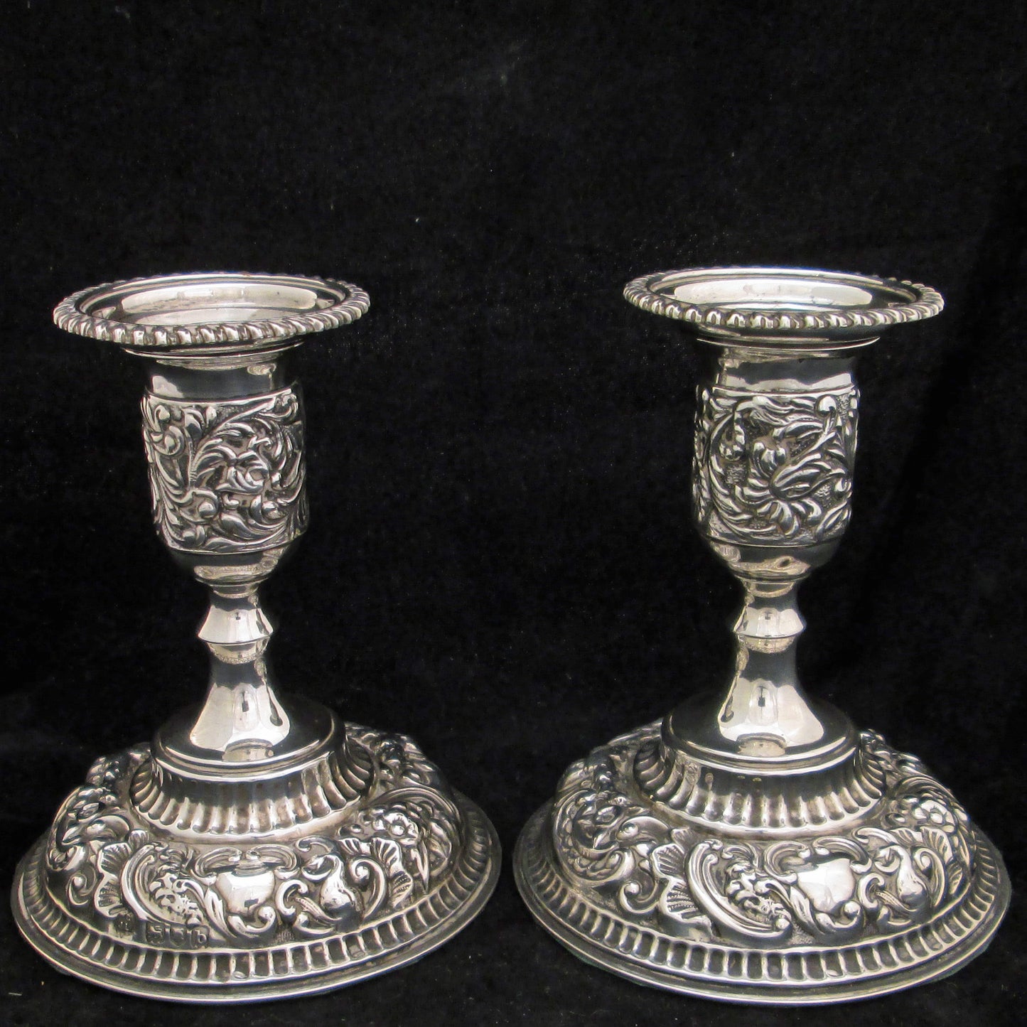 A pair of sterling silver embossed candlesticks.