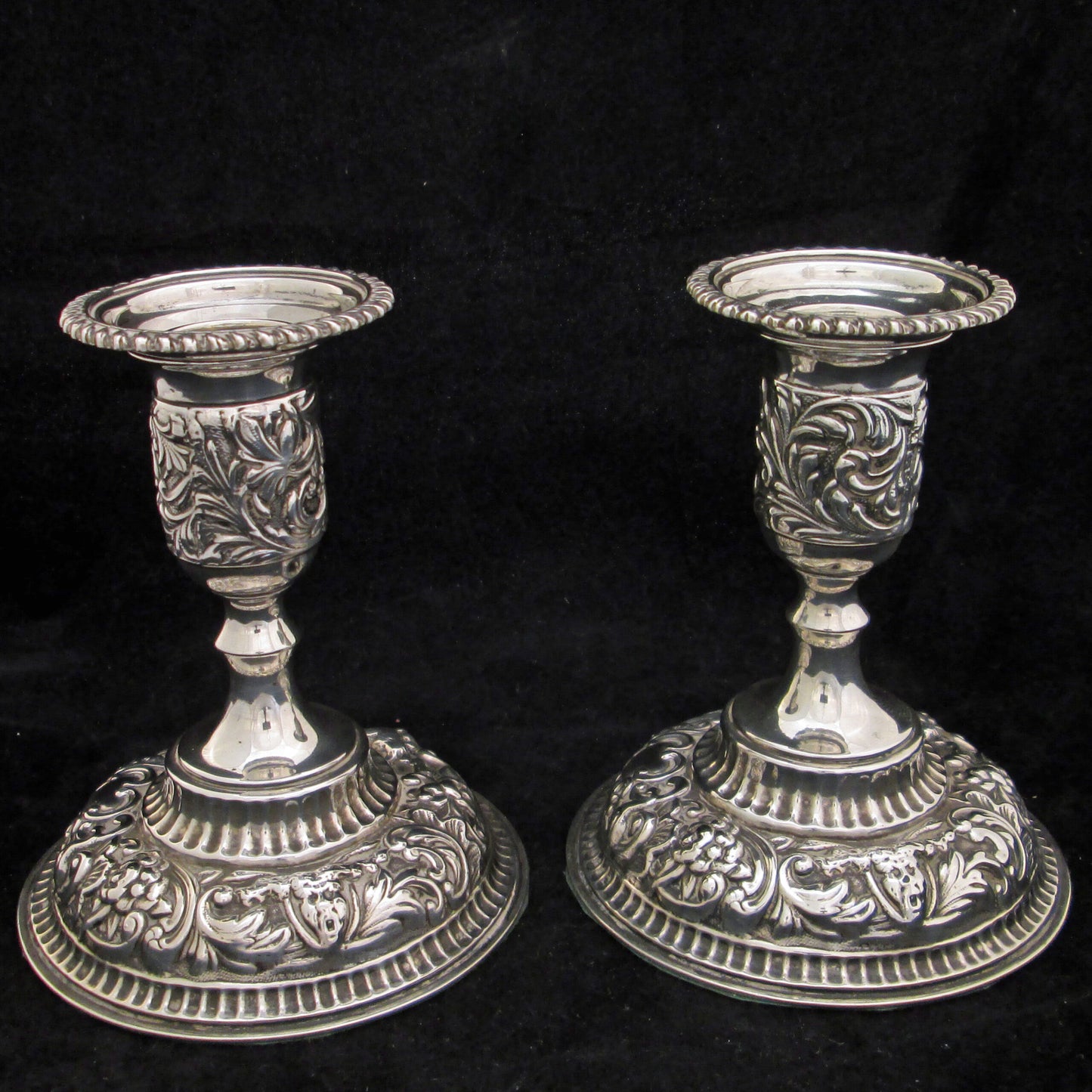 A pair of sterling silver embossed candlesticks.